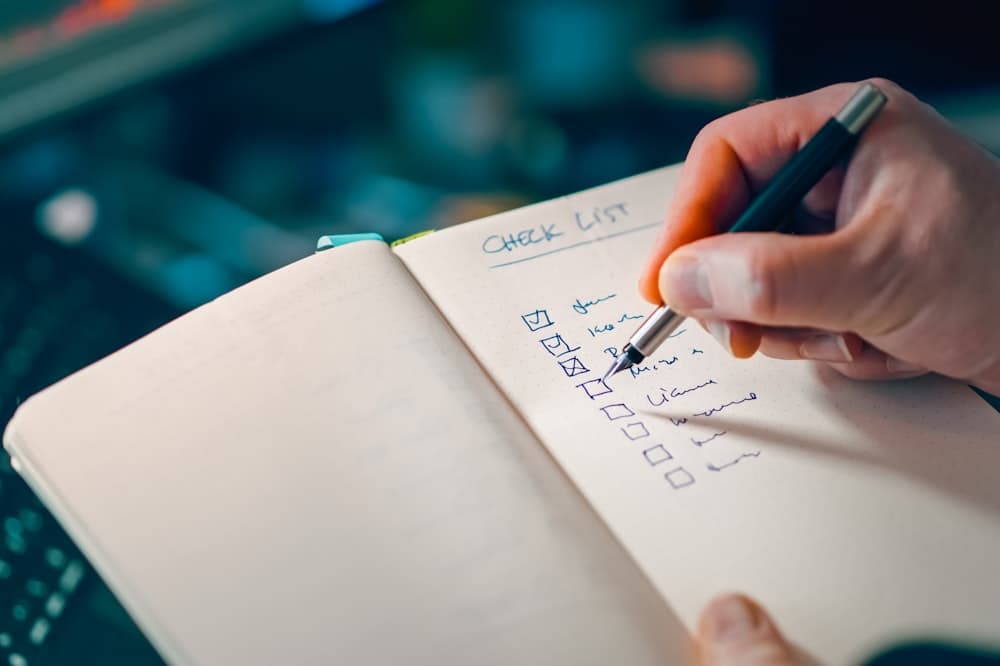 Mão escrevendo uma lista de verificação num caderno